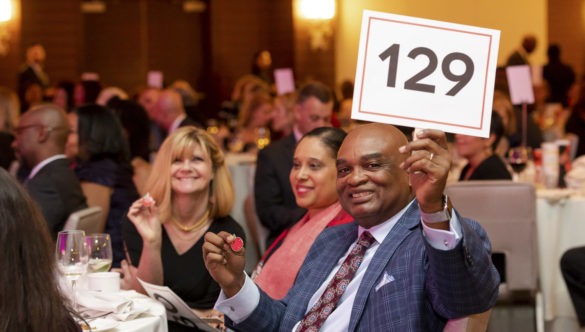 An event guest shows his auction number to the camera at a City Year event