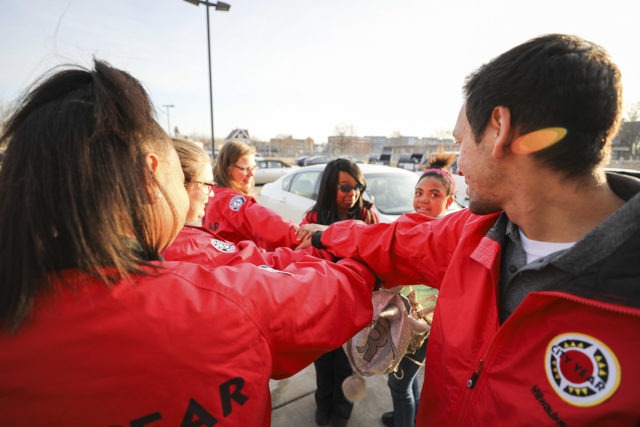 The camera looks over two City Year AmeriCorps members' shoulders as they put their hand in for a spirit break