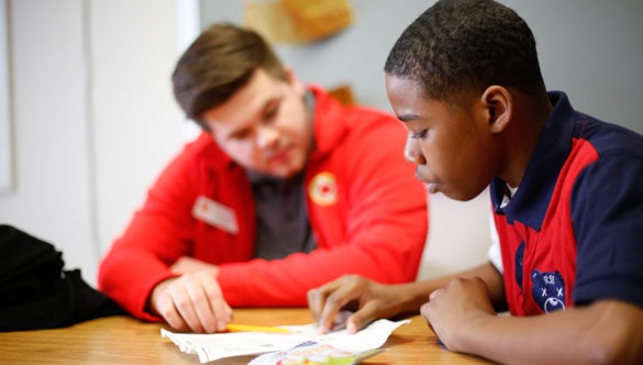 city year americorps member sits with a student at a desk as they review work