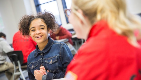 A young girl in a classroom taking with a City Year Americorps member