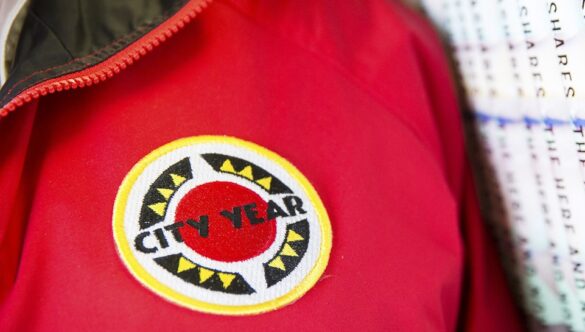 close up of AmeriCorps members' jacket, standing next to a row of books