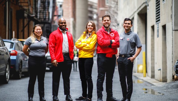 AmeriCorps members stand together in the street between city buildings.