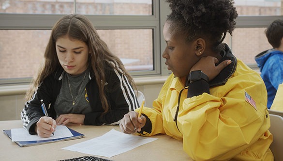 A CIty Year AmeriCorp member and a student seated at a desk studying