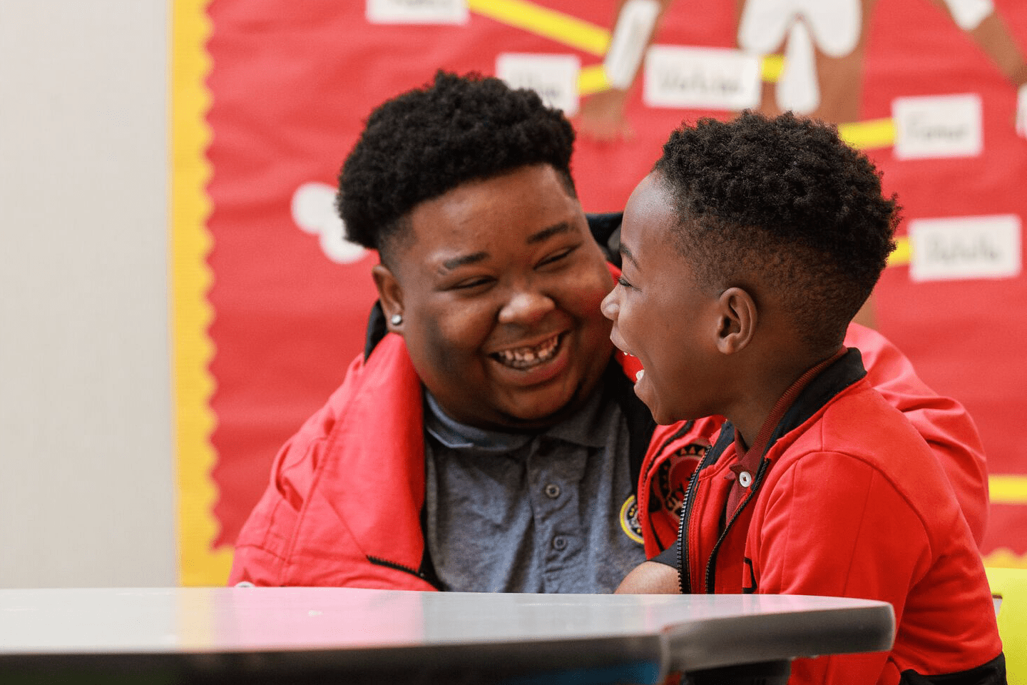 an elementary student and City Year AmeriCorps member laughing together